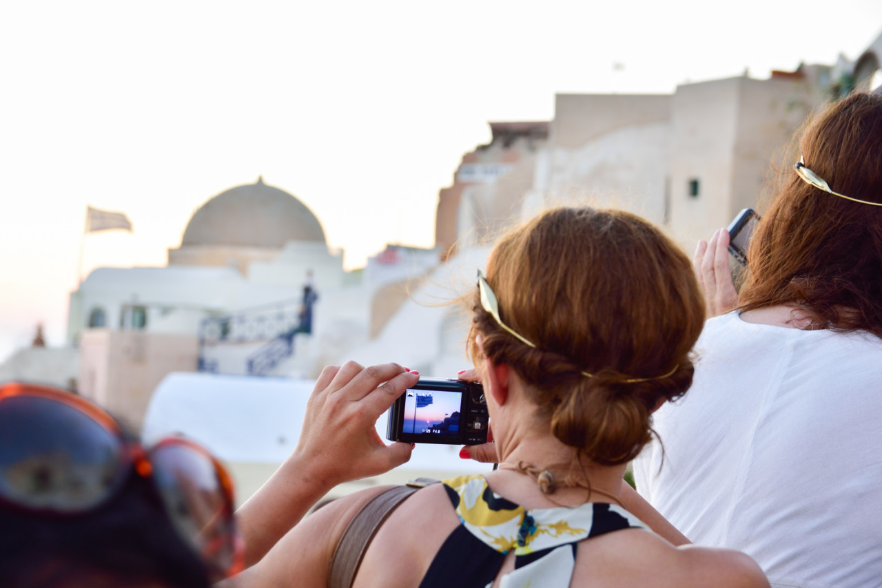 Woman taking photos with camera in Oia Santorini